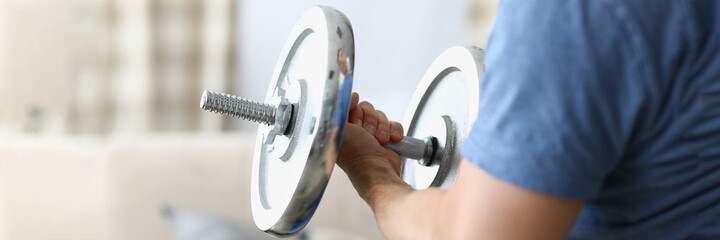 Man hand lifts heavy dumbbell while swinging biceps