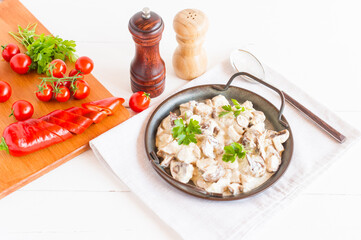 mushrooms in sour cream sauce in a frying pan on a white background. the concept of delicious healthy food.
