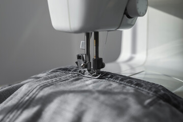 Denim textile on sewing machine closeup. Small business and slow fashion concept.