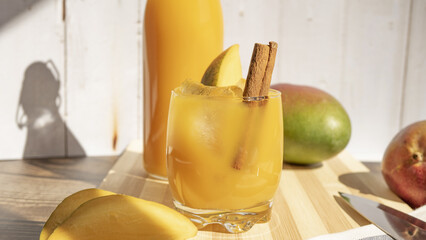 Closeup of a refreshing mango drink with a cinnamon stick, on a wooden surface