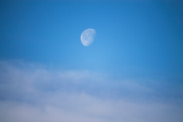 moon and clouds against blue sky