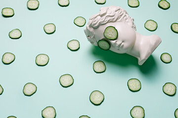 Fresh cucumber slices pattern and ancient bust with a cucumber slice mask on eyes on green...