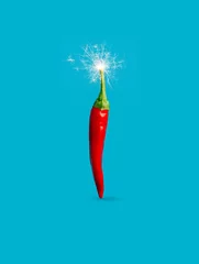Foto op Plexiglas Single red hot chili pepper with fire sparkler isolated on a vibrant blue background. Creative spicy vegetable food concept. New Year or Christmas party decoration. Fashion minimal art. © Aleksandar