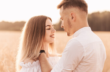 A young couple man and woman hug with tenderness in nature in the summer. Lovers