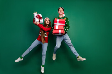 Photo of funny crazy couple hold pile giftbox enjoy jump flight wear hat ugly pullover isolated...