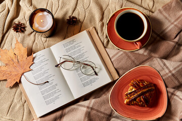autumn, season and leisure concept - open book of poems with glasses, cup of coffee, cinnamon bun...