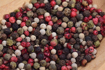  Colored peppercorns on a wooden bowl on a white background. Food. Spices.