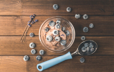 Chocolate ice cream with blueberries and lavender flowers in glass on the rustic background. Selective focus. Shallow depth of field.
