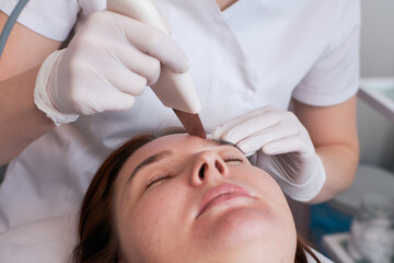Ultrasonic facial cleansing is a modern and safe deep facial cleansing procedure. Woman at the reception at the beautician during spa procedures.