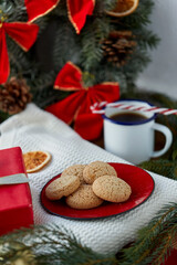 Fototapeta na wymiar bake, food and winter holidays concept - oatmeal cookies on red ceramic plate and christmas decorations at home