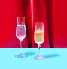 Vintage, luxurious crystal champagne glasses, sparkling drinks, aronia berries in it. Posh party concept, red velvet and blue background.