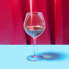 Striking crystal glass with red vine in it. Lovely red velvet and blue background.