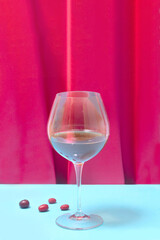 Deluxe crystal glass with red vine in it. Lovely red velvet and blue background, cornelian cherry beside it.