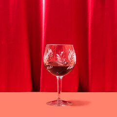 Posh crystal glass with dark drink in it. Lovely red velvet and terracotta background
