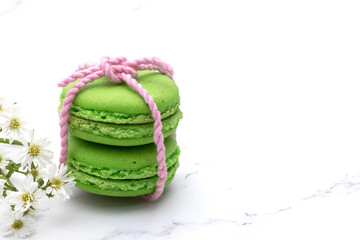 Closed up of two green macaroons tied with soft pink thread with beautiful tiny white flowers.