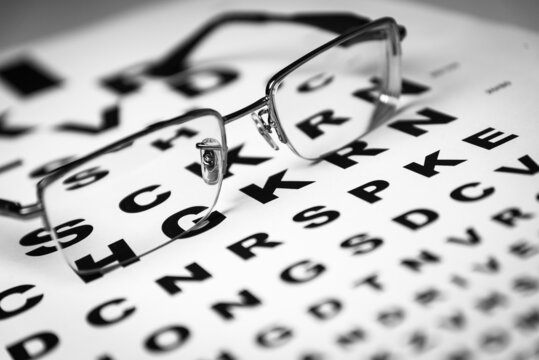 Black eye glasses on top of an eye chart. Shallow DOF. Selective focus