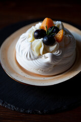 pavlova cake with berries on a dark background, soft focus