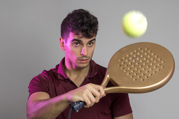 
a young man posing with a paddle racket in a studio background.