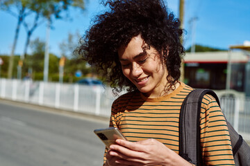 Fototapeta premium Smiling young woman reading a text by the roadside