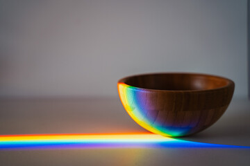 wooden bowl on grey background with rainbow light