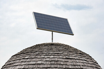 Solar panel on a wooden roof building in the form of a dome against cloudy sky
