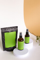 Close up black doy pack and two spray bottles with cosmetic product, green space for brand.