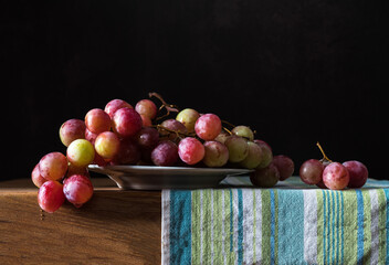 Pictorial still life with grapes. Still life with ripe pink grapes on a wooden table.