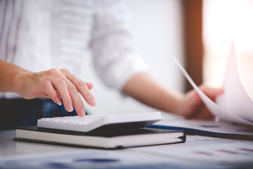 businessman or accountant who are using a calculator to calculate business data Accounting documents and laptop computer at the office business idea