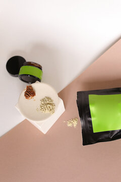 Black doy pack and jar with cosmetic products and green space for brand, clay powder on plate.
