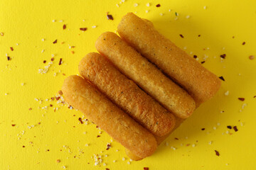 Cheese sticks and spices on yellow background