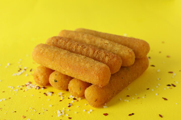 Cheese sticks and spices on yellow background