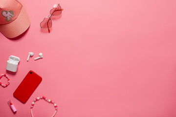 Top view with phone accessories and baseball cap. Phone and accessories with copy space on the pink isolated background top view.