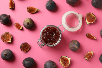 Jar with fig jam and ingredients on pink background