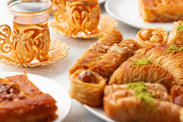 Various Turkish sweets and cup of tea on white textured background