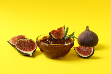 Bowl with fig jam and ingredients on yellow background