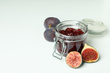 Jar with fig jam and ingredients on white background