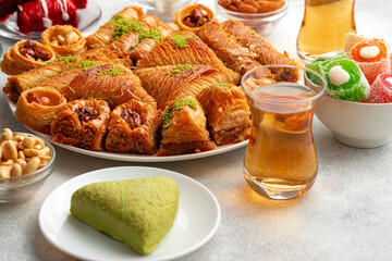Various Turkish sweets and cup of tea on white textured background