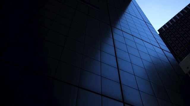 Metallic surface of a building shines dark blue. Moving