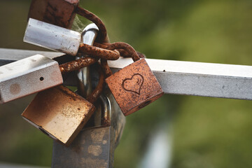 Rusty lock with a heart on a bridge. A promise of love.