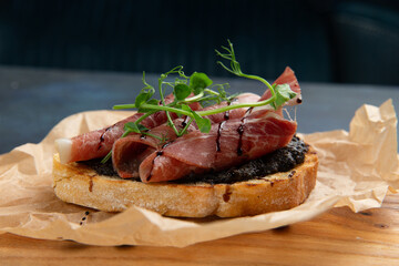 bruschetta with jamon and herbs. Against a dark background.
