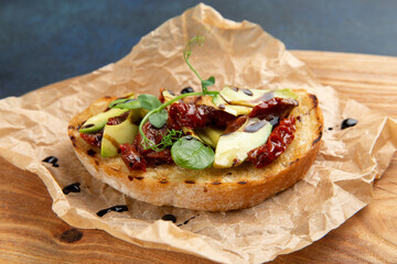 bruschetta with avacado and sun-dried tomatoes. Against a dark background.