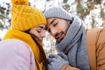 Fototapeta premium Smiling couple with closed eyes holding hands in winter park