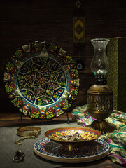 Vintage still life of traditional Turkish household items, a vase with jewelry, a silk scarf, a kerosene lamp against a wooden wall.