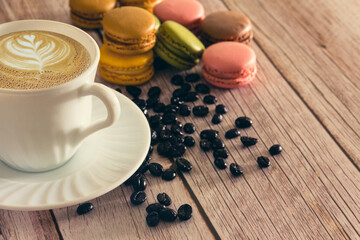 French macarons dessert with coffee cup and coffee beans. Copy space. Selective focus.
