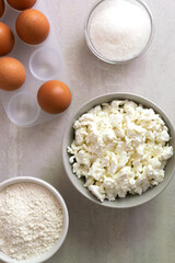 A set of ingredients for making muffins: cottage cheese, eggs, sugar, flour. Healthy nutrition concept. Vertical orientation.