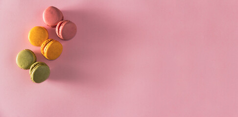 French pastel colored macarons dessert on pink background. Copy space. Selective focus.