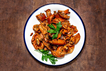 Fried Chanterelle  Mushrooms in a white plate  on wooden table. Copyspace. Top view, flat lay. Autumn Food concept..