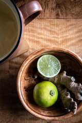 Hot drink with lime and ginger on a wooden table