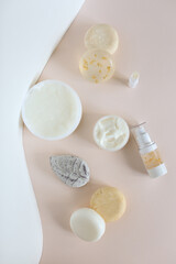 Top view of natural cosmetic products, organic soaps and spray bottle in light pink background.