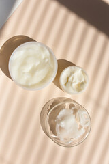Natural eco handmade facial cream or balm in white jar, striped shadow background.